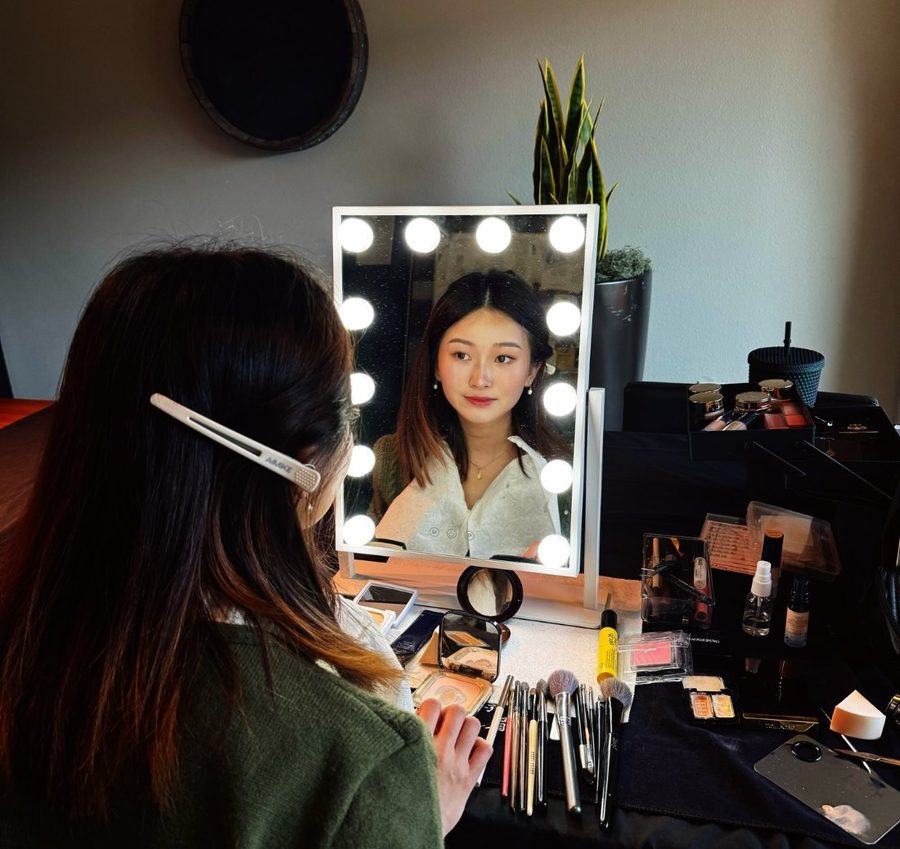 Student practising at a lit makeup mirror